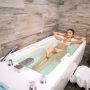 Young beautiful woman receives hydro massage and medical treatments for relaxation in modern spa